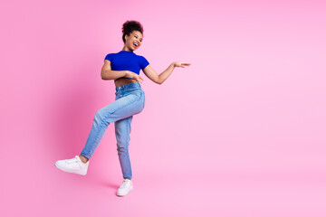 Joyful young woman dancing playfully in casual outfit against vibrant pink background capturing energy and fun