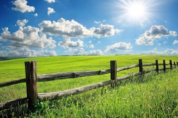 Rustic wooden fence with barbed wire and open field under blue sky