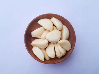 Bawang putih kupas. Peeled garlic isolated on white background. Perfect for design elements, or any commercial purposes. On a wooden bowl.