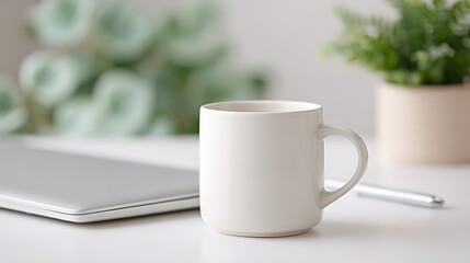 minimalist desk setup with closed laptop coffee mug and pen laid on pristine white surface