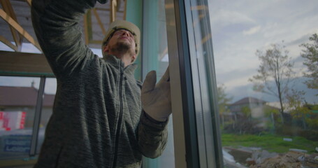 Worker examines window frame for precise alignment in residential construction site, quality control inspection in progress