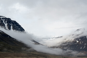 Snow-capped peak and low coastal mist in East Fjords, seen from ferry...