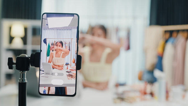 Close-up phone screen record Asia lady vlogger look phone camera apply lipstick on skin live sale online viral video selfie in IG story reel tiktok at home studio. Business online media concept.
