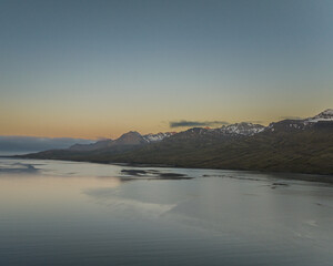 Golden hour aerial view of snowy mountains and valley in Faskrudsfjordur, Iceland...