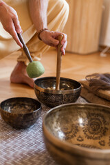 Sound healing ceremony in a yoga studio with Tibetan singing bowls, incense, and meditating participants. Peaceful atmosphere with natural light and warm tones
