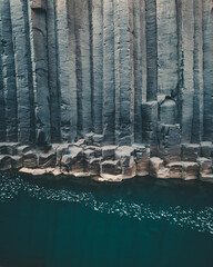 Basalt columns rise from turquoise water in Studlagil Canyon, Iceland...