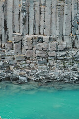 Close-up of basalt columns and turquoise river in Studlagil Canyon, Iceland..