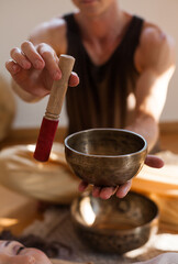 Sound healing ceremony in a yoga studio with Tibetan singing bowls, incense, and meditating participants. Peaceful atmosphere with natural light and warm tones