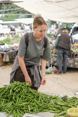 Young woman choosing fresh organic vegetables at a local market. Concept of eco lifestyle,...