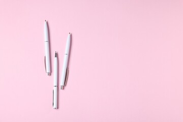 Ballpoint pens on pink background, flat lay. Space for text