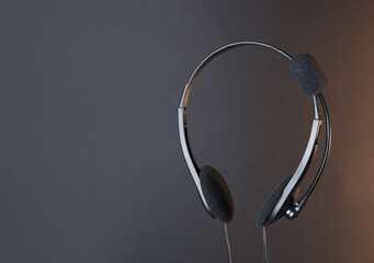 Headset with microphone in air on dark background, space for text