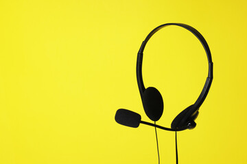 Headset with microphone in air on yellow background, space for text