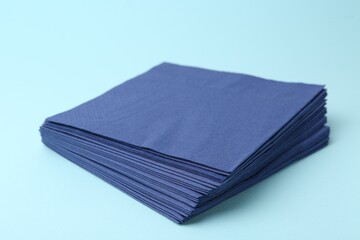 Stack of disposable paper handkerchiefs on light blue background, closeup