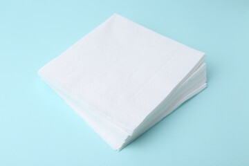 Stack of disposable paper handkerchiefs on light blue background, closeup