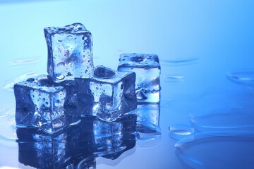 Cubes of clear ice on light blue background, space for text