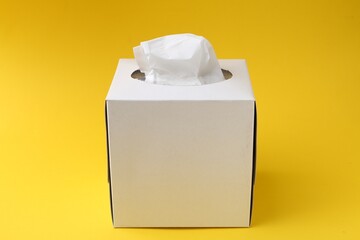 Box with paper handkerchiefs on yellow background