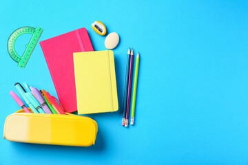 Fototapeta na wymiar Pens and other stationery on light blue background, flat lay. Space for text