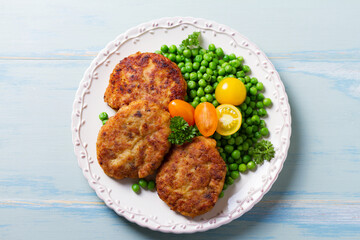 Fish cakes with green peas. Fish patties or burgers. View from above, top studio shot