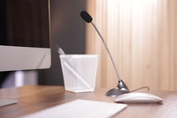 Microphone and computer on wooden desk indoors