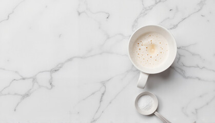 White coffee cup with frothy milk and spoon on marble surface  
