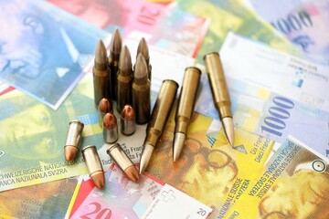 Swiss franc banknotes and bullets. The current francs money bills and ammo lies on table