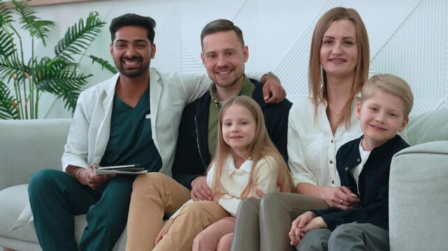 Compassionate healthcare worker sitting with supportive family members on hospital sofa, connecting through empathetic communication and shared wellness journey