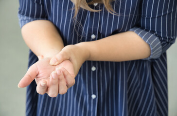 Middle aged Asian woman suffering from wrist pain, health care concept image of trigger finger, CTS or carpal tunnel syndrome, gout disease, arthritis inflammation, office syndrome, closeup shot