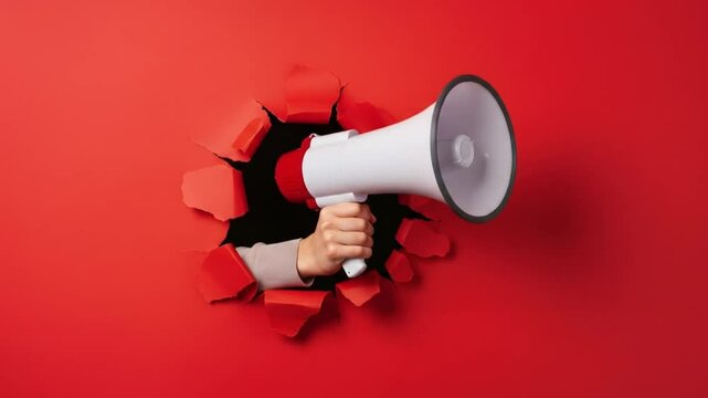 Hand holding megaphone piercing red background