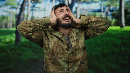 Obraz premium Hispanic man in military uniform looking distressed in a green park surrounded by trees under a bright sky.