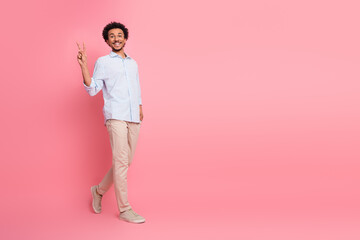 Confident young male with a relaxed demeanor gesturing a peace sign while posing against a vibrant...