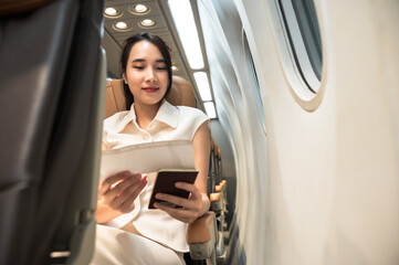 Fototapeta premium Asian female traveler siting at window seat on commercial airplane