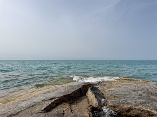 Rocky shore and clear water of Issyk-Kul under a vast sky