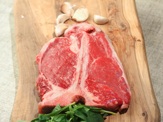 Luxurious T bone steak on a wooden cutting board with garlic and
