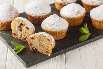 Festive muffins with candied fruits, raisins, spices and powdered sugar close-up on a board on a wooden table. Horizontal
