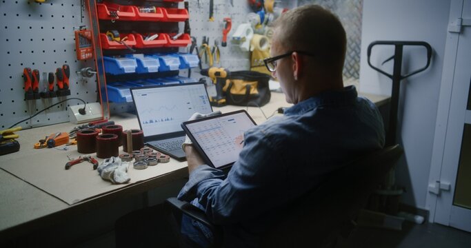 Employee Checking Real-Time Stocks and Exchange Market Charts Using Digital Tablet and Laptop. Man Making Cryptocurrency Investments During Working Hours in Workshop, Combining Job with Online Trading