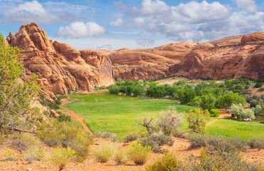 Green field surrounded by red rock cliffs, Moab, Utah, USA