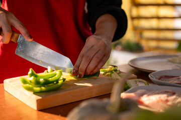 A person is cutting vegetables on a wooden cutting board
