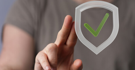 Image of a hand with a checkmark inside a shield.  Represents security, verification, and data...
