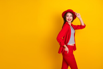 Glamorous stylish woman in a vibrant red outfit poses confidently on a bright yellow background showcasing trendy fashion
