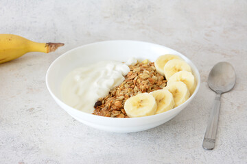a white bowl with Granola, Yogurt and Banana close up 