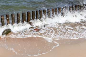 Wooden breakwater structures along a sandy beach with the ocean waves