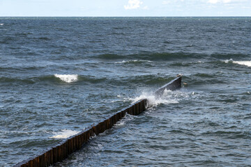 Fototapeta premium Dynamic image showcasing ocean waves striking a wooden breakwater