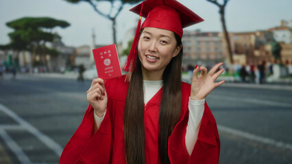 Woman in red graduation gown holds a japanese passport on an urban street, symbolizing travel and...