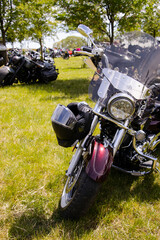 Shiny black motorcycles parked on grass during a sunny biker rally. Chrome details gleam in the...