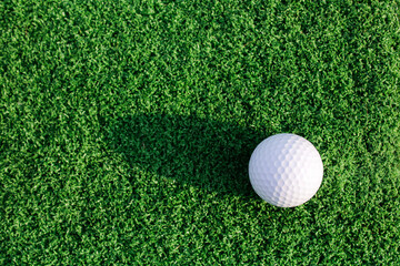 Golf Ball on Lush Green Grass with Shadow in Bright Natural Light