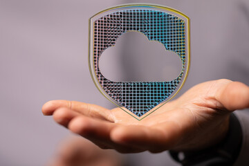Image of a hand holding a cloud icon inside a protective shield.  Represents cloud security and...