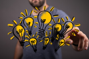 Concept image showing a man interacting with multiple light bulb illustrations, symbolizing...