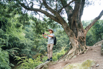asian man taking picture while hiking