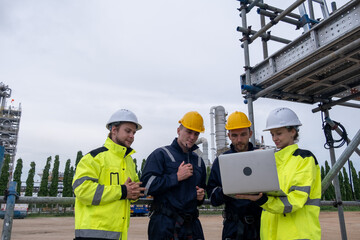 Engineers review project data on laptop at industrial site during overcast day