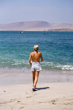 Tourist walking on la mina beach in paracas national reserve, peru
